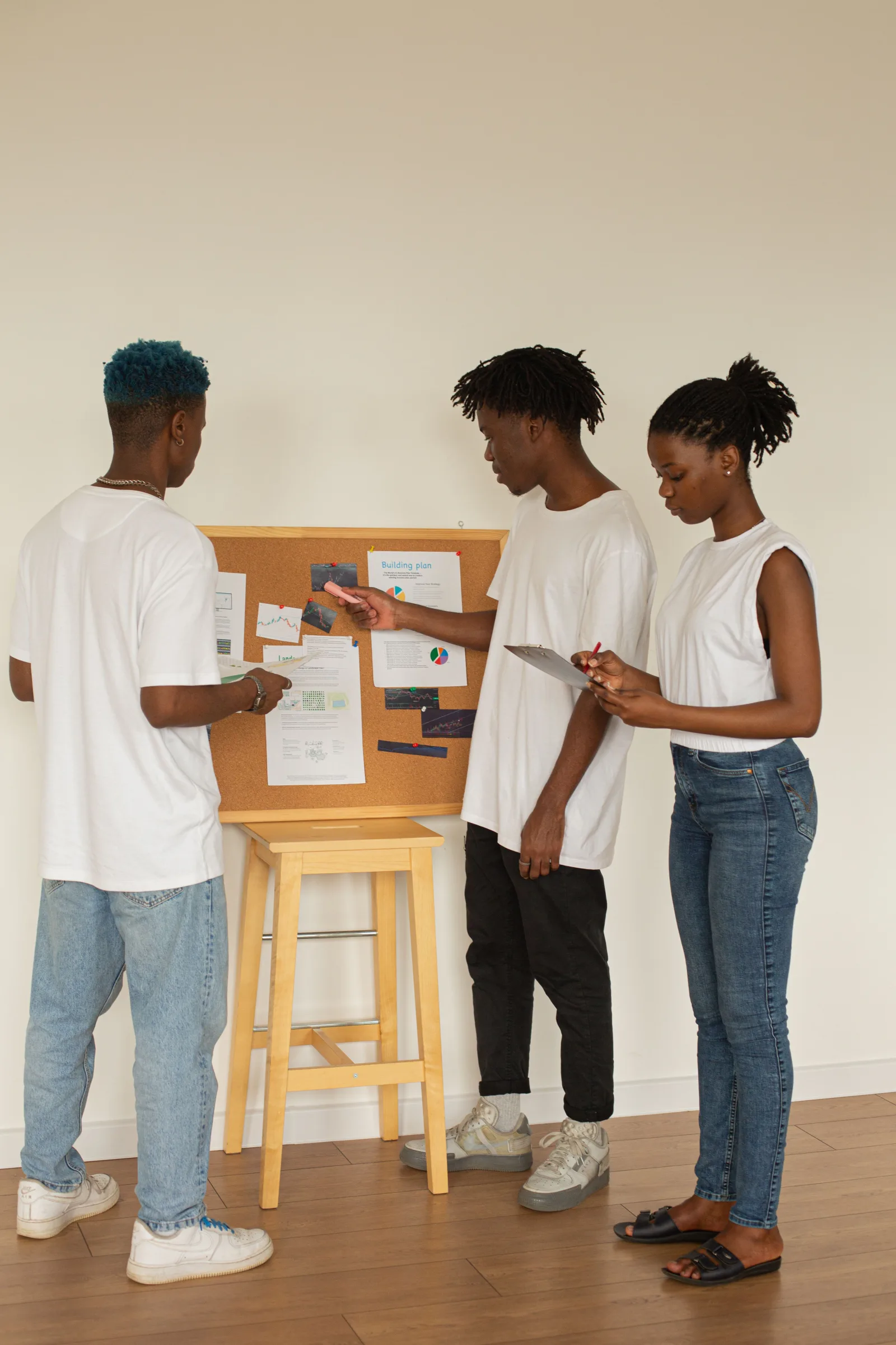 Trois jeunes adultes préparent un projet autour d’un tableau